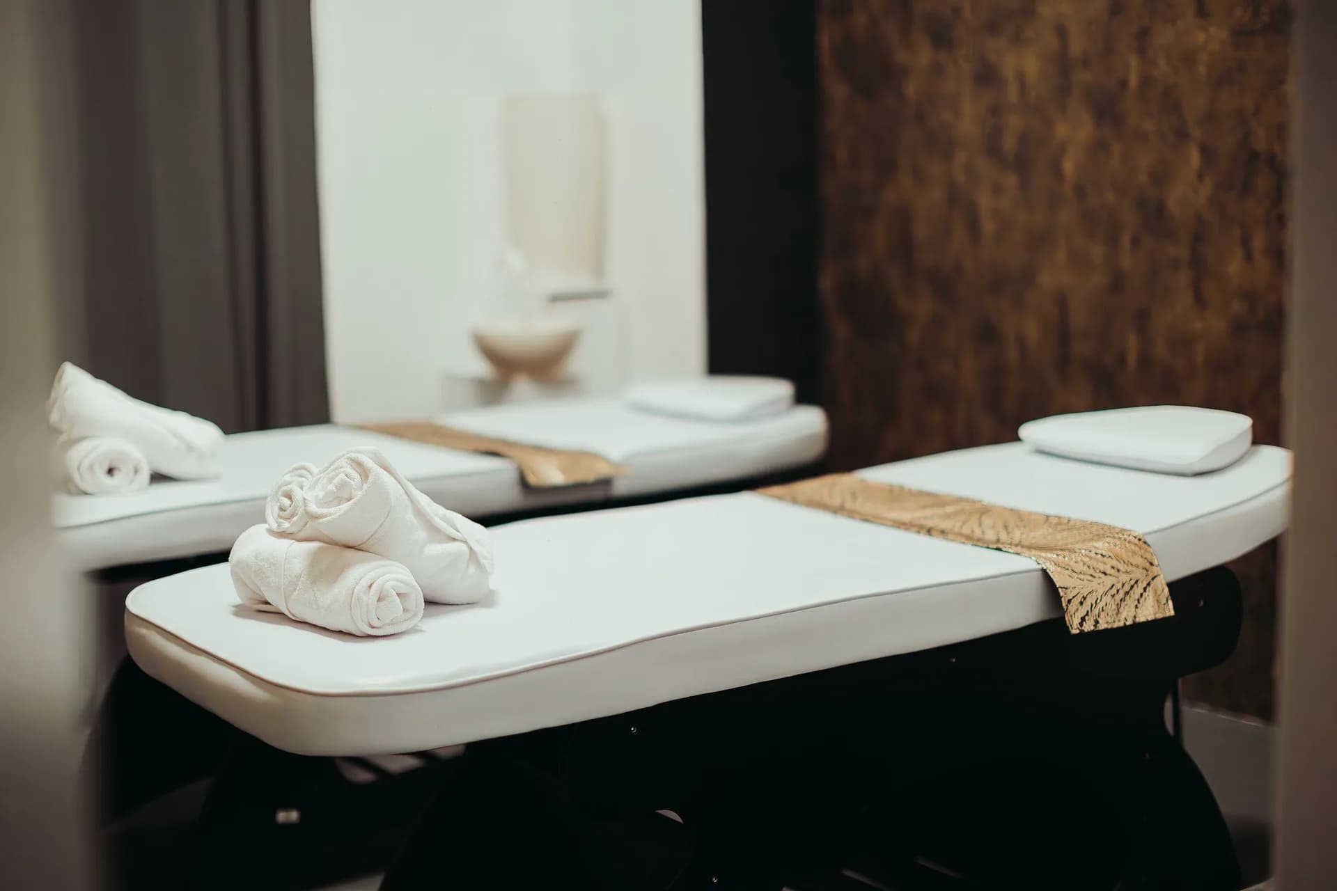 Enlarge photo: Close-up of aromatic massage oil bottles and a bowl of dried herbs on a wooden tray