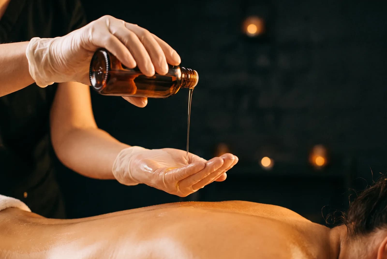 Enlarge photo: A therapist working the back and neck muscles of a client lying under a gold drape