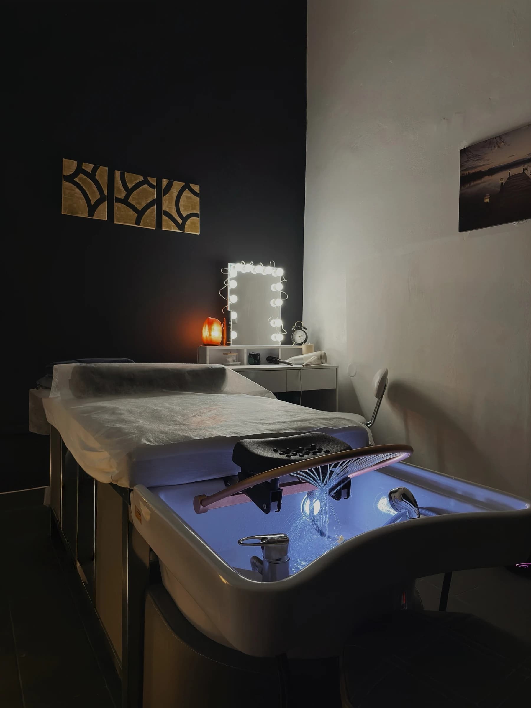 Terapeutka masíruje ramena a šíji hosta ležícího na masážním lehátku v salonu Massage DeLuxe
