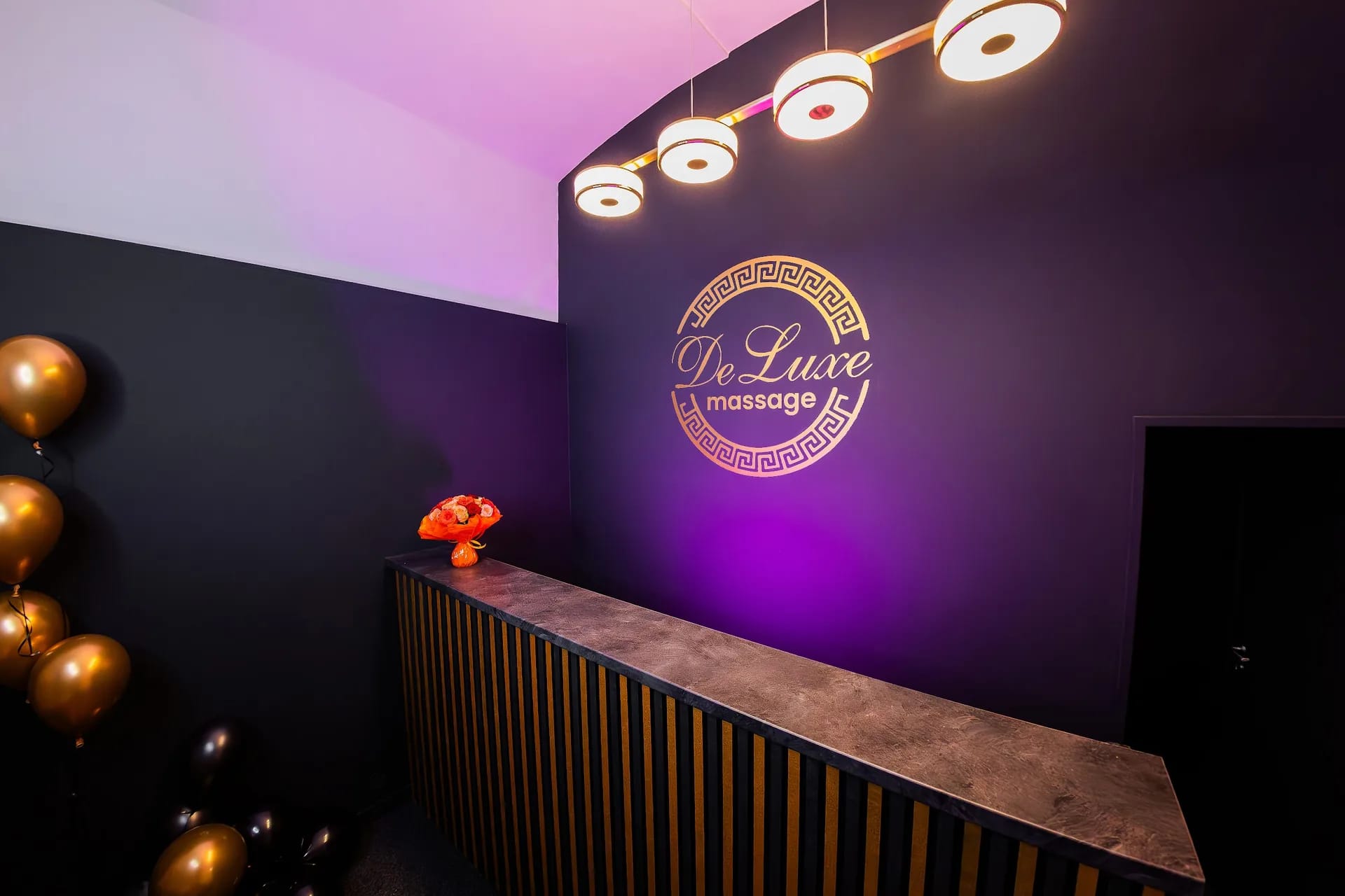 Recepce salonu Massage DeLuxe s podsvíceným zlatým logem